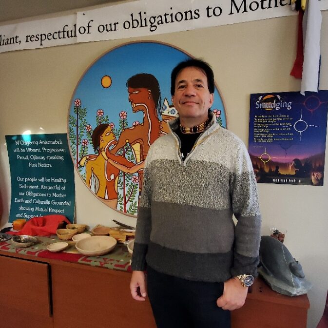 Photo of Rick Mclean standing in front of a indigenous display in the background